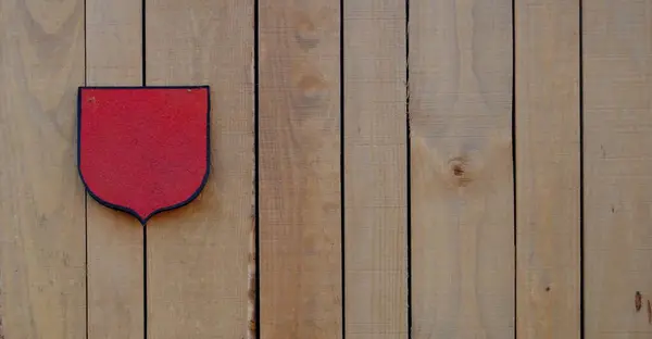 Küçük kırmızı bayrak, kalkan, tahta bir çite sıkışmış, ahşap doku.