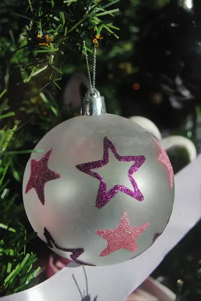 Noel ağacında asılı parlak mor bir yıldızla şeffaf bir Noel balosu.