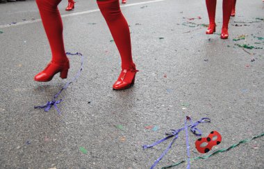 Dansçıların ayaklarının kırmızı ayakkabı, konfeti ve düşmüş maskelerle dolu bir karnavalın zemininde.