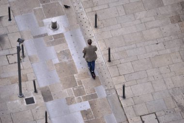 Yaya bir şehir caddesinde scooter kullanan biri, hava manzaralı, insansız hava aracı manzaralı.