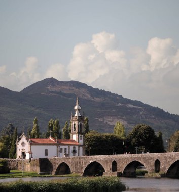 Portekiz 'in kuzeyinde yer alan Ponte de Lima şehrindeki antik köprü ve kilise, Camino de Santiago dağının arkasında.