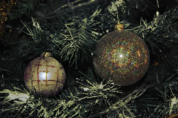 Altın toplar parıltılı ve koyu arkaplanlı Noel ağacında asılı.