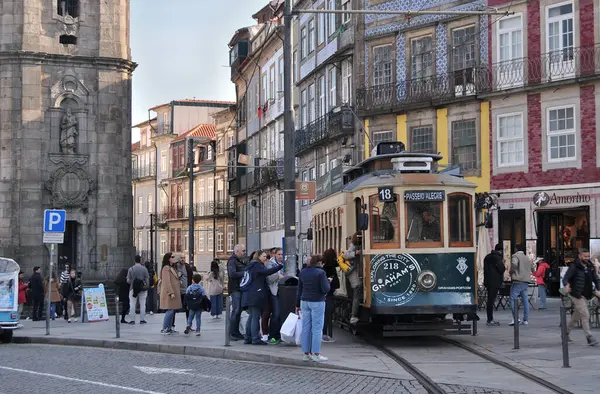 Portekiz şehir merkezindeki Porto 'da geleneksel ve tarihi ulaşım, arka planda Clerigos Kulesi ve insanlarla dolu bir tramvay, toplu taşıma ve turizm
