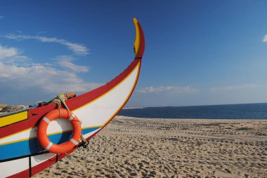 Ufuk çizgisi, kırmızı, sarı, mavi çizgiler ve turuncu şamandıra, beyaz arka plan ile tezat oluşturan bir balıkçı teknesinin pruvası.