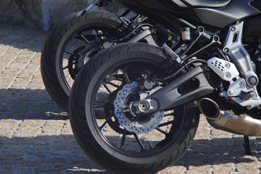 İki motosiklet tekerleği, arka arkaya park etmiş motosikletlerin fotoğrafları.