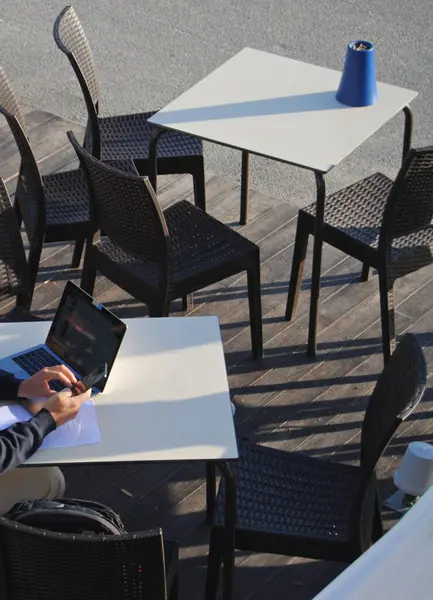 Dışarıda çalışan, dışarıda bir masada dizüstü bilgisayar kullanan biri.