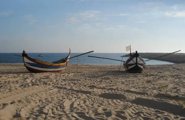 Balıkçılık endüstrisinin farklı renklerinde iki tekne kumsalda durdu.