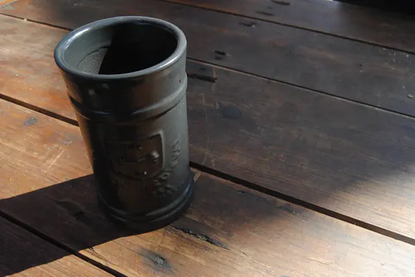 Eski bir ortaçağ masasında duran antika siyah kilden bir bardak.