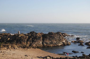 İki çocuk kumsalda deniz suyunun, deniz manzarasının, yaz sahilinin, tatilin, boş zamanların ve tatilin yanında kumsalda oynuyorlar.