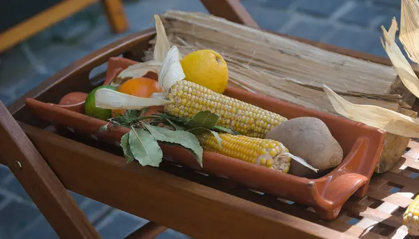 Pişmeden önce geleneksel bir yemeğin hazırlanması, kil, mısır, patates, limon ve portakalda servis edilmesi