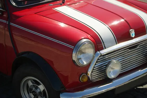 Kaputunda beyaz çizgiler olan kırmızı eski bir İngiliz arabasının önünde.