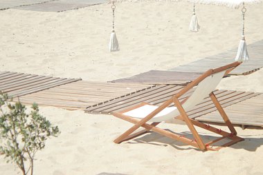 Plajda, kumsalda, kumsalda güneşlenen, tropikal dekorlu, plajda boş, üzerinde kimse olmayan bir sandalye.