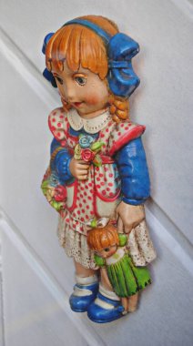 Beyaz ahşap bir duvara asılı duran iki bebek.