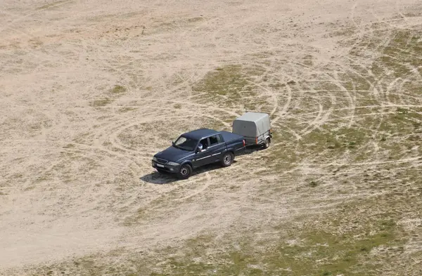 Açık bir arazinin ortasında, tekerlek izleri olan bir kamyonet. Etrafta dolaştıktan sonra.