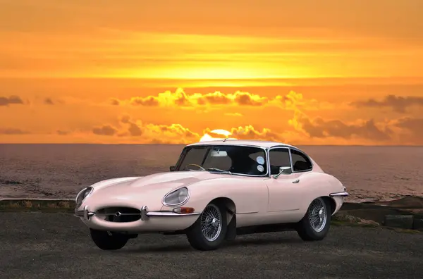 Gün batımlı klasik spor araba, İngiliz markalı eski beyaz araba, deniz kenarında gün batımında park edilmiş.