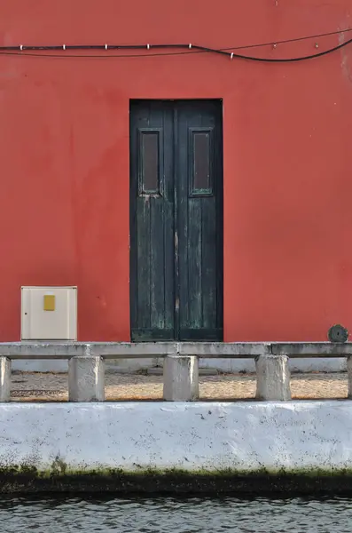 Duvarla zıt renkte, yıllanmış ahşap kapı suyla ve benzer geometrik şekillerle uyuşuyor.