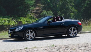 Siyah Alman spor arabası Cabriolet dağlık bir çevrede bir yola park etmiş.