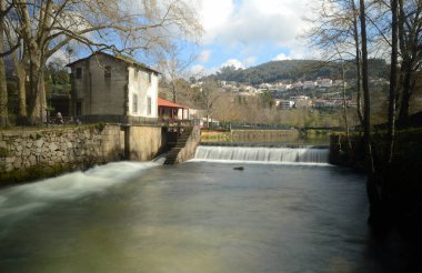Portekiz 'in kuzeyindeki Guimaraes' de Vizela şehrinde nehir şelalesi olan bir parkta eski ve yaşlanmış değirmen evi.