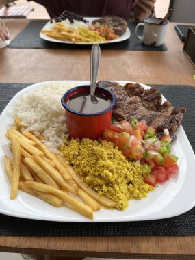 Geleneksel Brezilya yemeği: pirinç, fasulye, barbekü eti, farofa ve patates kızartması, Brezilya 'nın zengin mutfağını temsil eden lezzetli ve klasik bir kombinasyon.