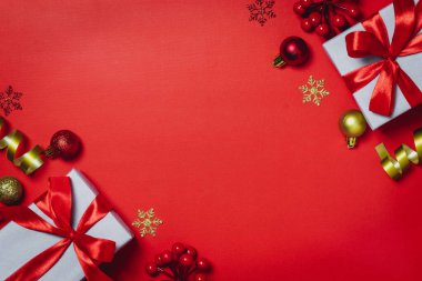 Noel kompozisyonu. Hediyeler, kırmızı arka planda kırmızı süslemeler. Düz konum, üst görünüm, kopyalama alanı