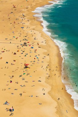 Praia de Nazare sahilinin havadan görünüşü turistlerin, Naziler ve Portekizler 'de yaz tatili boyunca dinlendiklerini, güneşlendiklerini ve okyanusta yüzdüklerini gösteriyor.
