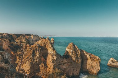 Turistler Ponta da piedade 'de bir uçurumun kenarına inşa edilmiş tahta merdivenlerden aşağı iniyorlar, Portekiz, Lagos' ta kaya oluşumları ve okyanus manzaralı bir yer.