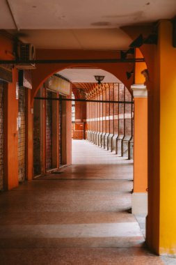 Bolonya, İtalya 'da turuncu sütunlu ve kemerli boş bir sütun manzarası mimari güzelliği gözler önüne seriyor ve derinlik hissi yaratıyor.