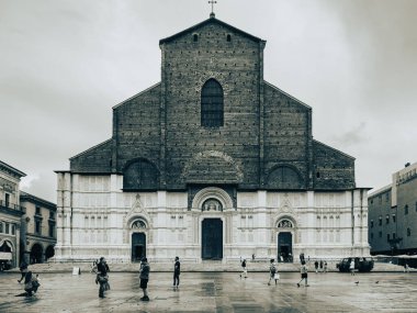 Arka planda San Petronio Bazilikası olan Piazza Maggiore 'de yürüyen turistler, bulutlu bir günde İtalya' nın Bolonya şehrinde büyük bir dönüm noktası.