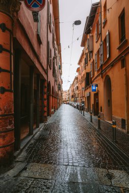 Yağmur, İtalya 'nın Bolonya kentindeki geleneksel İtalyan binalarının ılık turuncu renklerini yansıtan kaldırım taşlı bir caddeye yağdı ve pitoresk bir şehir manzarası yarattı.