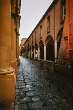 Islak taş kaldırımlar, Bolonya, İtalya 'daki tarihi binaların atari salonlarını yansıtıyor ve yağmurdan sonra güzel bir sahne yaratıyor.