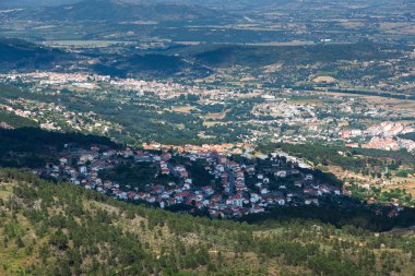 Aerial view of covilha, a city nestled amidst rolling hills and valleys, showcasing the urban sprawl and surrounding landscape under the bright summer daylight of portugal clipart