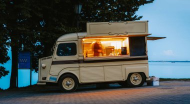 Alacakaranlık 'ta gölün kenarına park etmiş eski bir yemek kamyonu. Şef içeride yemek hazırlıyor, sokak yemekleri satıyor ve açık hava yemekleri yapıyor.