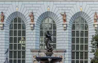 Gdansk, Polonya 'daki Neptün çeşmesi, bronz heykel, süslü detaylar ve büyük cephaneliğin kemerli pencereleri ve asker heykelleri.