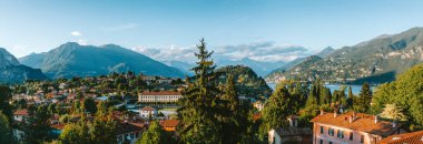 Sıcak güneş ışığı, Bellagio, İtalya 'nın renkli binalarını ve yemyeşil bahçelerini aydınlatmakta, göl kenarı ve Grigne dağları, güzel bir zemin oluşturmaktadır.