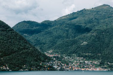 İtalyan Alpleri 'ndeki Como Gölü bulutlu bir gökyüzünün altındaki sakin sulara yansıyan dağ yamaçlarındaki köylerin huzurlu bir manzarasını sunar. Nesso 'dan alındı.