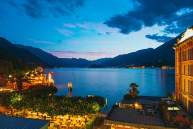Bellagio 'da alacakaranlık, İtalya' da aydınlık binalar, renkli gökyüzü, dingin sular ve çevresindeki dağlar resim gibi bir manzara yaratır.