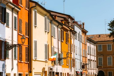 Parma, İtalya 'da renkli bir binadan sallanan İtalyan bayrağı güneşli bir yaz gününde büyüleyici caddeye bir neşe katıyor.