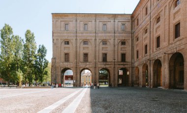 Palazzo della pilotta avlusunda yürüyen turistler, Parma, İtalya 'nın tarihi merkezinde güneşli bir yaz gününün tadını çıkarıyorlar.