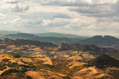 Ekilmiş tarlalar ve yuvarlanan tepeler San Marino kırsalında bulutlu bir gökyüzünün altında kırsal güzelliğin ve tarım mirasının huzurlu bir manzarasını sunuyor.