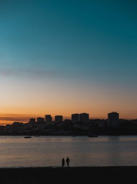 İki kişi Douro nehrinin üzerinde güzel bir günbatımının tadını çıkarıyor. Arka planda Porto şehri manzarası var. Huzurlu ve romantik bir atmosfer yaratıyorlar. Cabedelo 'dan, Vila Nova de Gaia, Portekiz