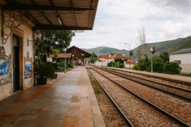 Pinhao, alijo, Portekiz 'deki boş tren istasyonu platformunda geleneksel azulejo fayansları, ahşap bir istasyon binası ve gerçek vilanın dağlık arazisine giden demiryolu rayları bulunuyor.