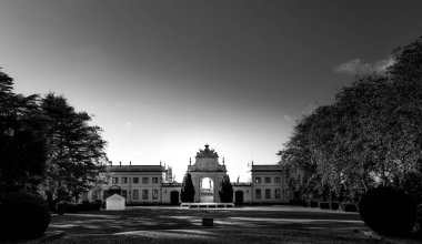 Sunlight illuminates the grand entrance gate of palacio de seteais in sintra, portugal, creating a striking contrast against the dark sky in this black and white photograph clipart