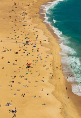 Praia de Nazare sahillerinde güneşlenen ve Naziler, Portekiz 'deki Atlantik Okyanusunda yüzen turistlerle güneşli bir yaz gününde, siyanodan hava manzarası
