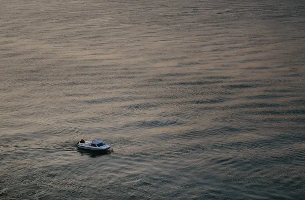 Gün batımında sakin bir denizde sakin bir şekilde seyreden küçük motorlu tekne suda rahatlatıcı dalgalar yaratıyor. Sahne huzurlu ve huzurlu, huzur ve rahatlama çağrıştırıyor.