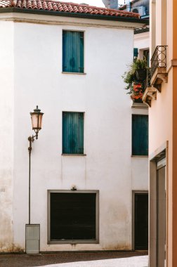 Mavi panjurlu beyaz bina, Via Teatro Dolfin, Treviso, Veneto, İtalya 'da kapalı dükkan ve sokak lambaları tipik İtalyan mimarisini gösteriyor.