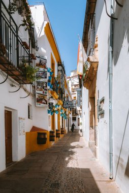 Güney İspanya 'da popüler bir turizm merkezi olan Cordoba, Endülüs' te bitki ve bayraklarla süslenmiş beyaz ve sarı binalarla geleneksel dar sokaklar