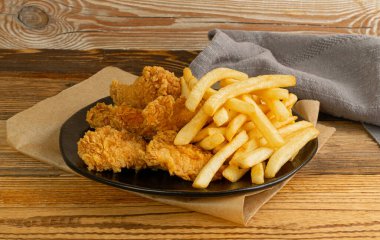 Breaded Fried Chicken Wings, Fingers and Drumsticks on Wooden Rustic Background Side View. Hot Crispy Chicken Nuggets, French Fries, Fillet Strips, Meat Pieces in Breadcrumbs
