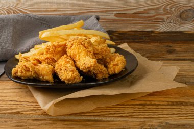 Breaded Fried Chicken Wings, Fingers and Drumsticks on Wooden Rustic Background Side View. Hot Crispy Chicken Nuggets, French Fries, Fillet Strips, Meat Pieces in Breadcrumbs
