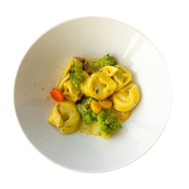 Cooked Tortellini in White Bowl. Agnolotti, Cappelletti, Dumplings, Stuffed Pasta, Tortelloni, Ravioli, Cappelletti, Uszka with Romanesco, Mushrooms and Vegetables Top View