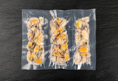 Packed Frozen Mussels, Unshelled Clam, Frozen Peeled Mussel, Cold Mussels Meat, Iced Seafood, Cooked Shellfish on Black Stone Background Top View